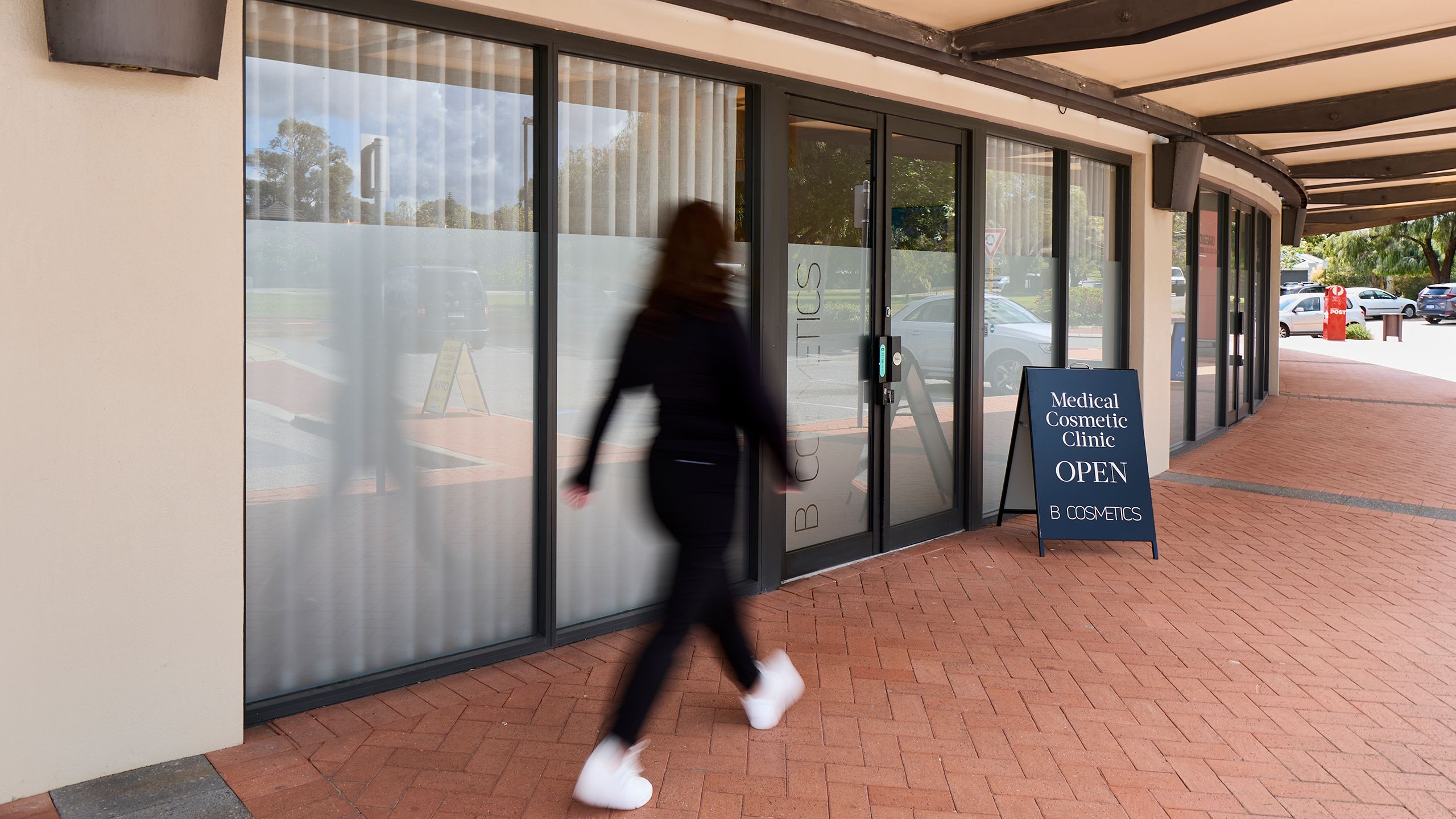 A shot of the front doors of B Cosmetics, with a person walking by.