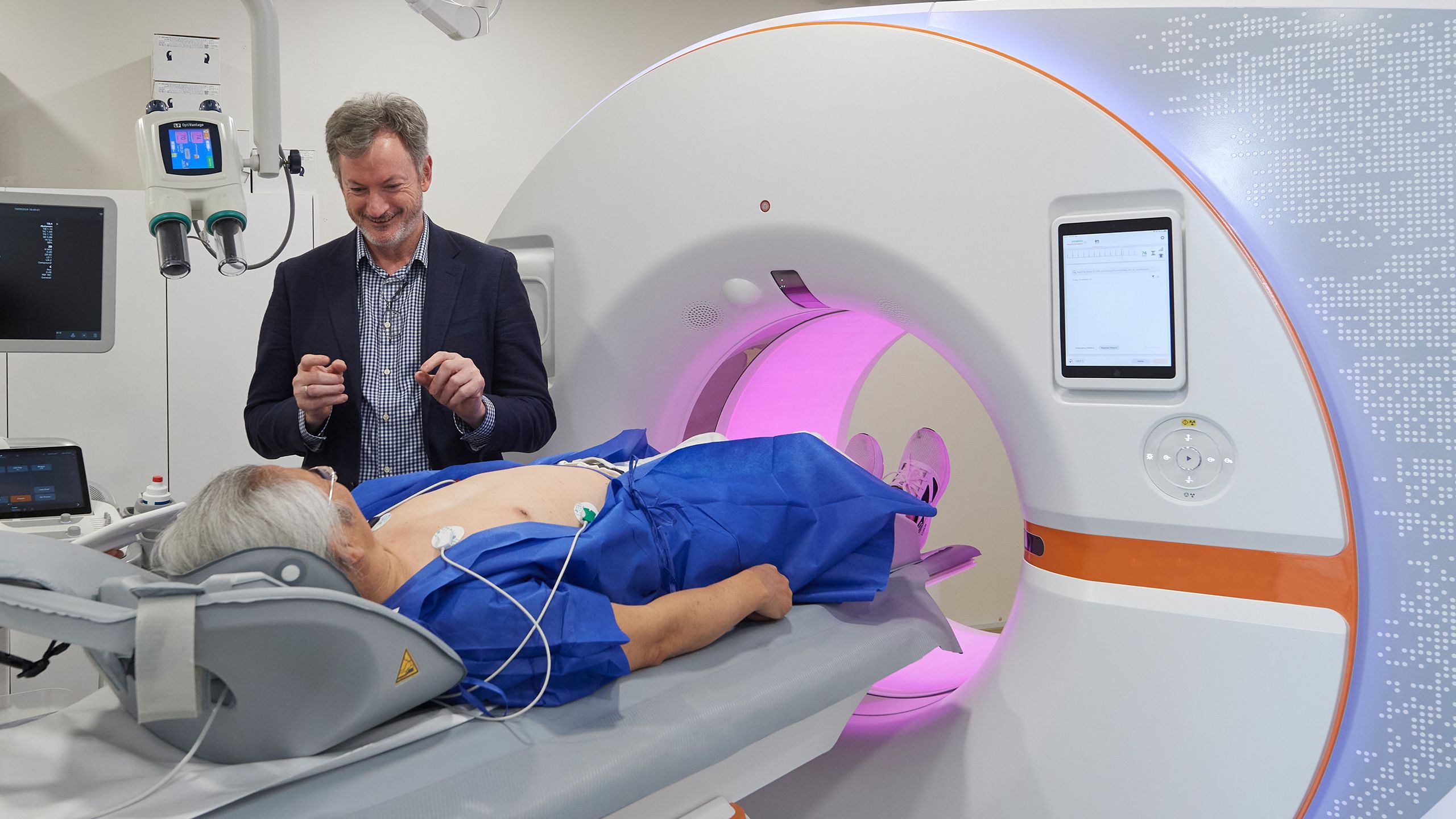 Radiologist, Dr Conor Murray stands over a patient lying down before a CT scan machine at his clinic, ChestRad.