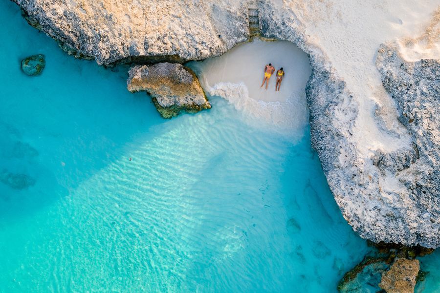Two people relaxing on a beach from a birds eye view.